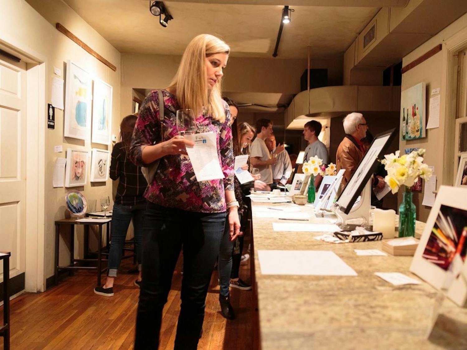 Sarah Yarbrough looks at a table of art at the Mixed Concrete Art Auction on Saturday night.