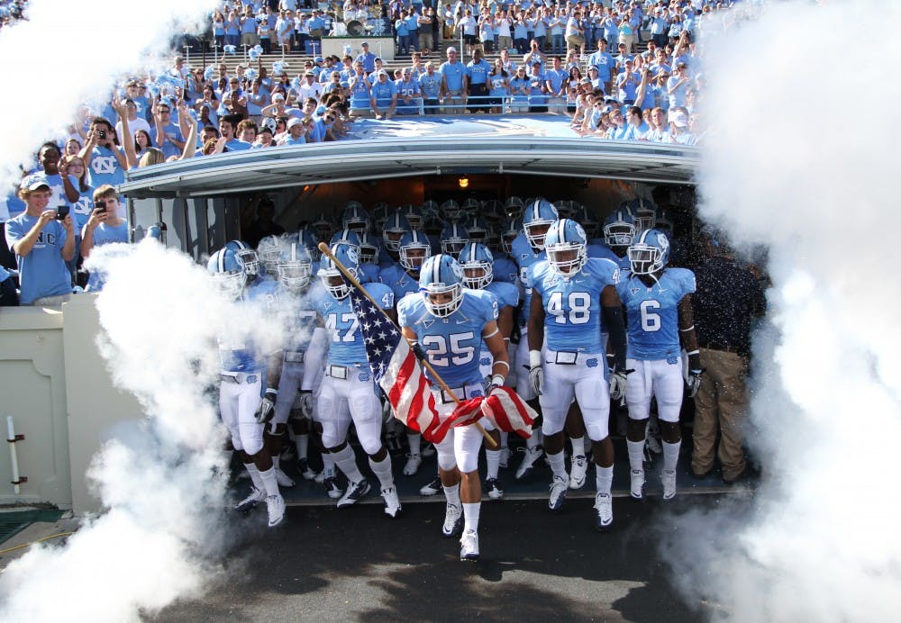 Matt Merletti, a redshirt junior safety, leads UNC out of the tunnel with the flag his brother Mike gave him from his military stationing in Afghanistan. 
