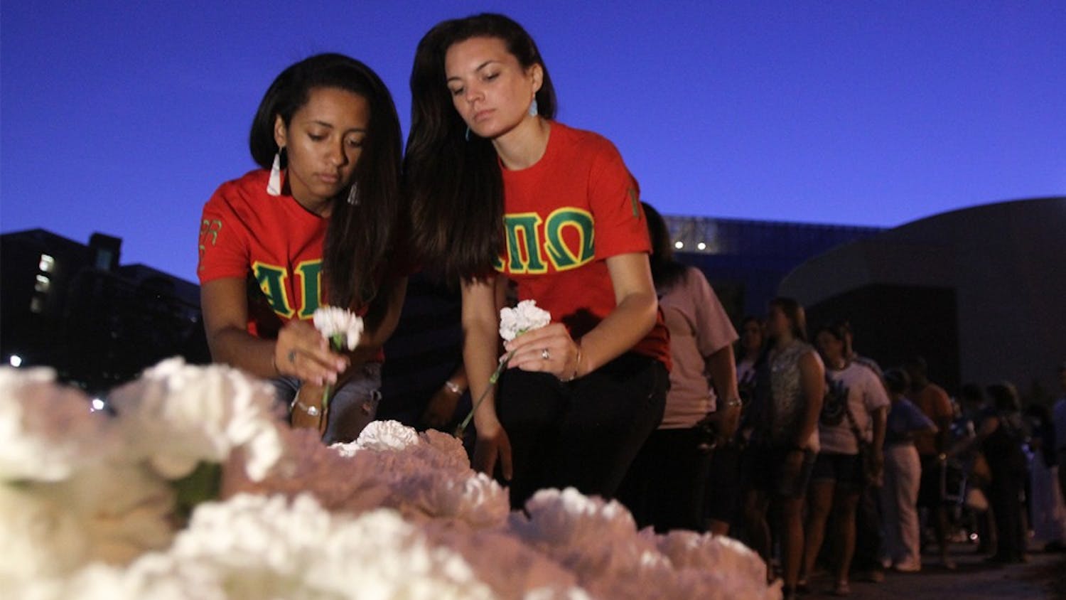 From left, Taylor Springs of the NC State chapter of the Native American Sorority Alpha Pi Omega and Brooke Spaulding of the Campbell chapter pick up carnations for the silent walk held for the anniversary of Faith Hedgepeth's death on Saturday, Sept. 7, 2013.&nbsp;