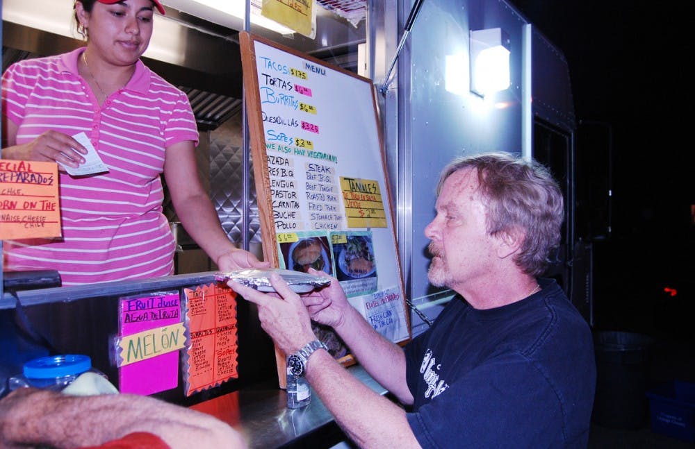 Mark Byrley, 56 from Carrboro, receives some food at the taco truck in Carrboro near Harris Teeter.  Several food trucks operate in Carrboro, but regulations for licenses and permissions for space for food trucks have stopped some from operating them in Chapel Hill.