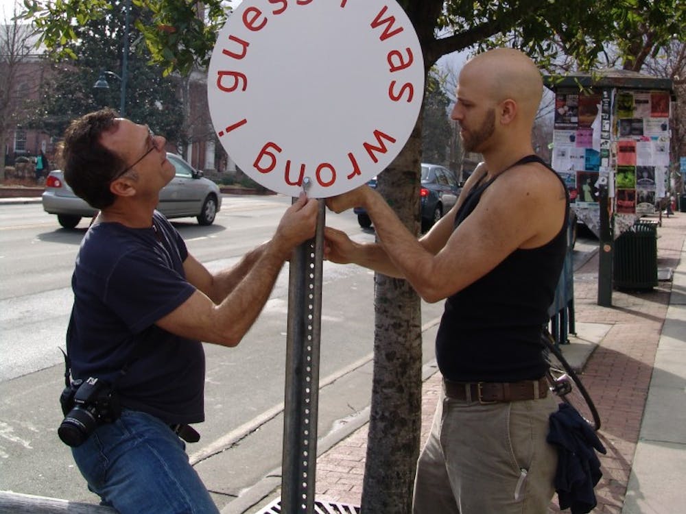 	Artist Gregory Sale (left) and Ackland preparator Andrew Nagy install one of Sale’s signs on Franklin Street. Photo by Emily Bowles. 
