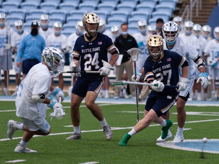 UNC senior attackman Chris Gray (4) attempts to scoop a ground ball before Notre Dame first-year defenseman Ross Burgmaster (27) during the game against Notre Dame on April 25, 2021 at Kenan Stadium. The Tar Heels' defeated the Fighting Irish 12-10.