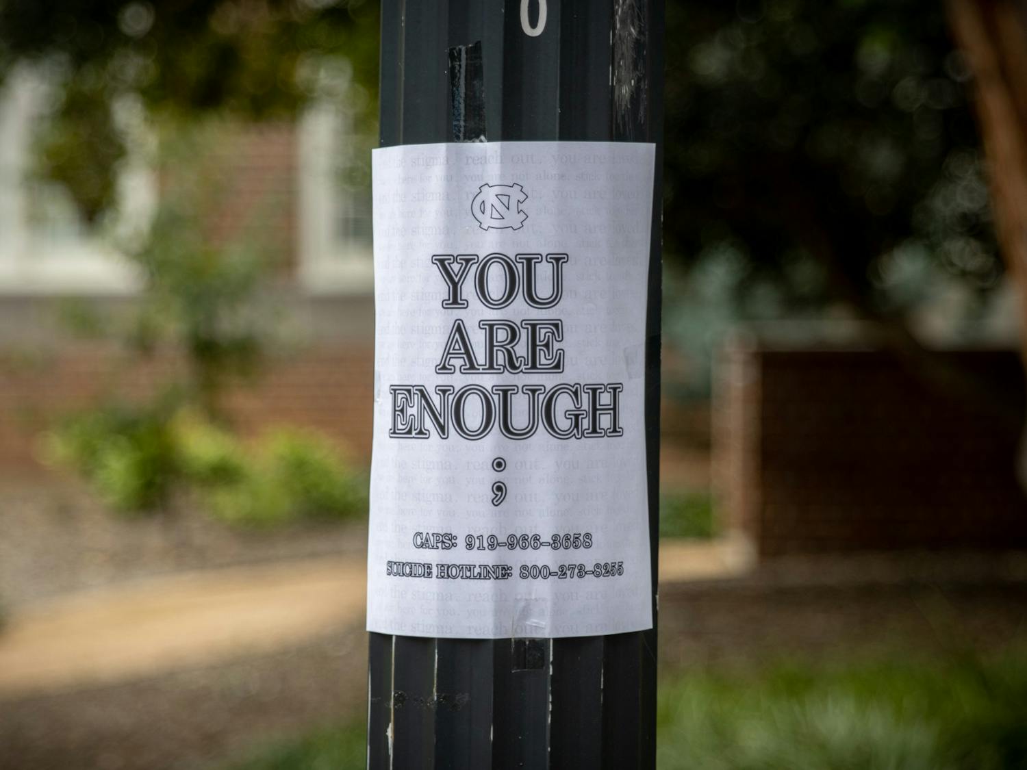 A sign listing numbers for the suicide hotline and CAPS is posted on a light pole outside of Murphey Hall on Oct. 11.
