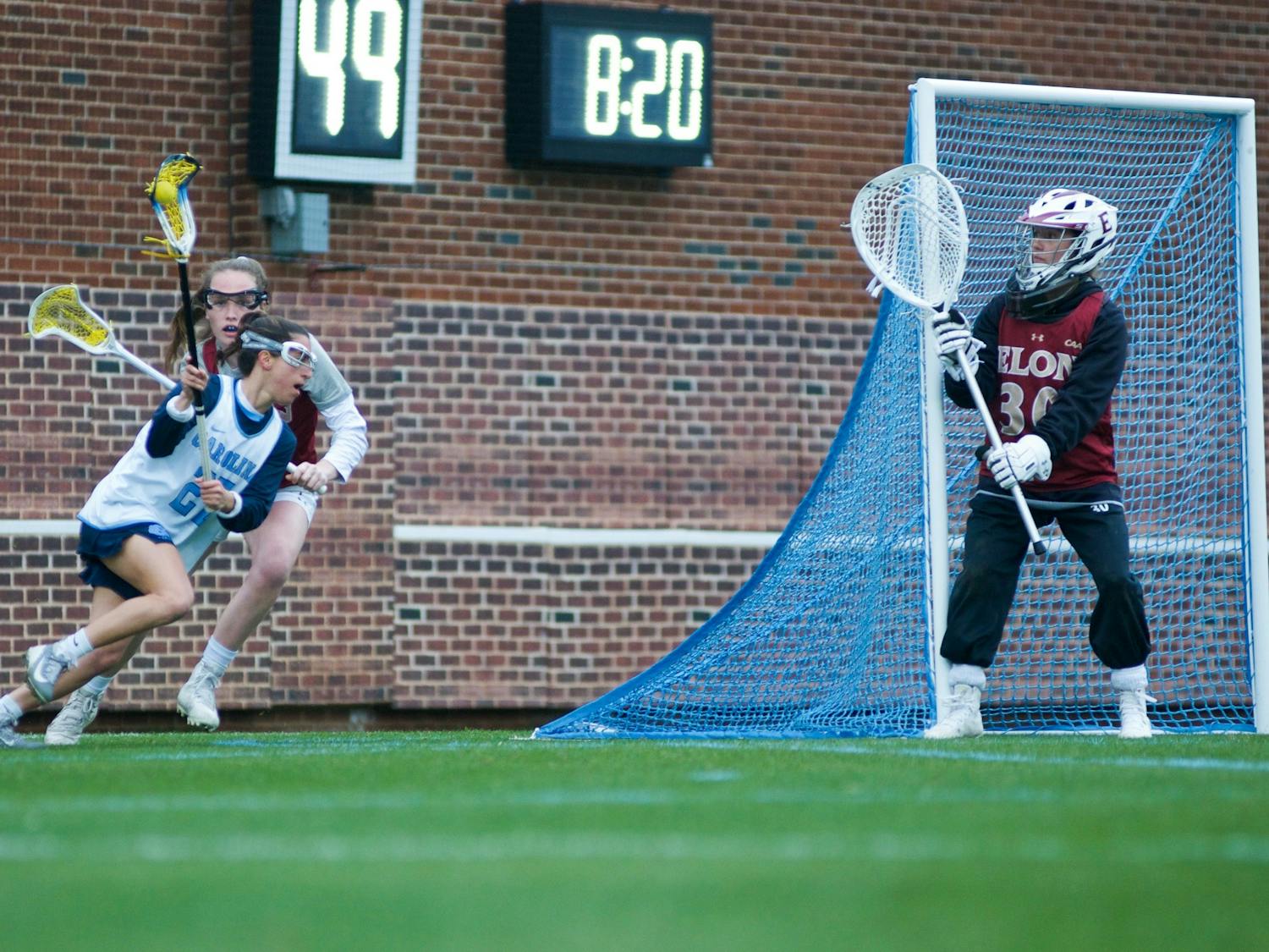 UNC senior midfielder Marisa Divietro (27) charges past Elon freshman defender Hannah Mccarthy (7) to attempt a shot on goal. The Tar Heels would start off the season with a 20-3 victory over Elon during the exhibition match on Feb. 1, 2020, at Dorrance Field. 