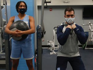 Women's basketball strength coach Caleb Krueger assists first-year guard Kennedy Todd-Williams during a preseason workout October 1, 2020 in Carmichael Arena. Photo courtesy of UNC Athletics Communications.