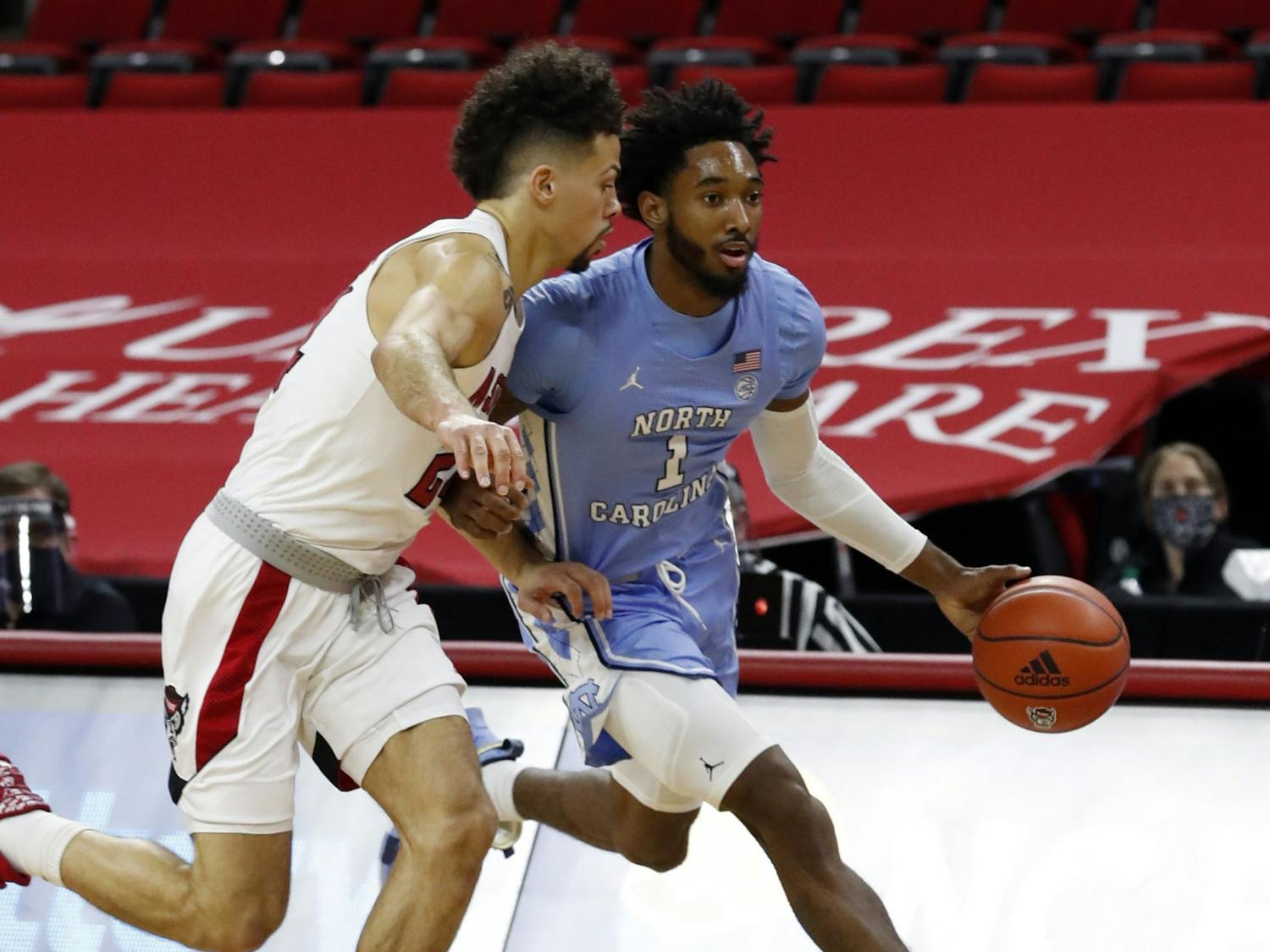 North Carolina's Leaky Black (1) drives past N.C. State's Devon Daniels (24) during the first half of N.C. State’s game against UNC at PNC Arena in Raleigh, N.C., Tuesday, December 22, 2020. Photo courtesy of Ethan Hyman.
