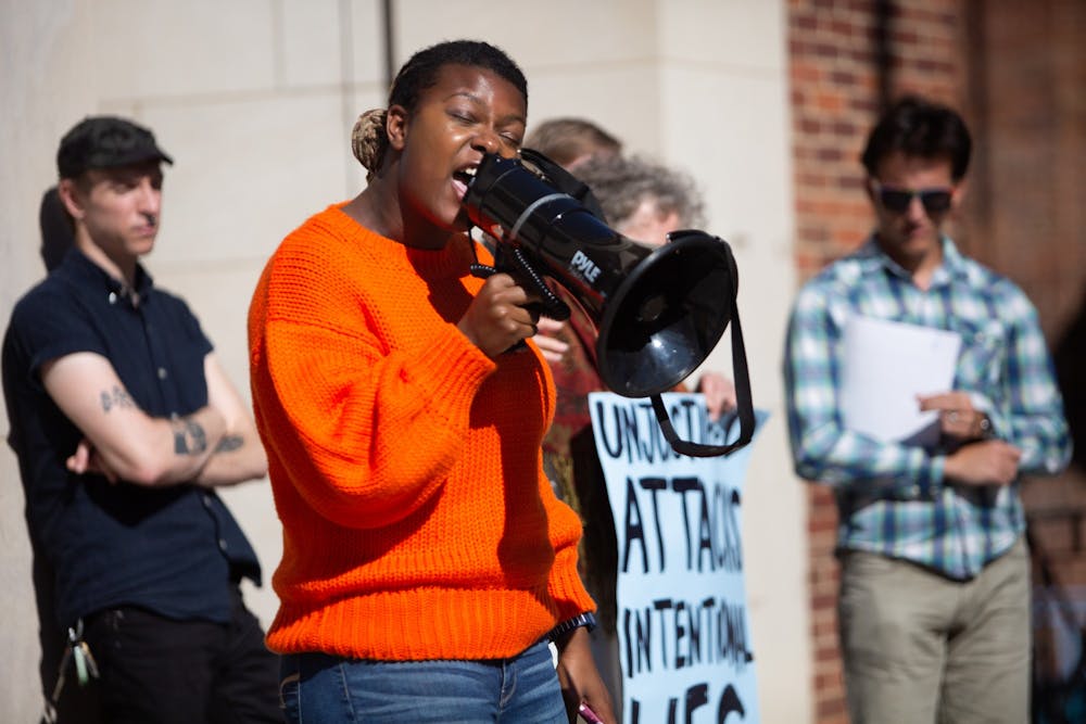 De’Ivyion Drew, a sophomore and member of the Campus Safety Commission, speaks into a megaphone to address a crowd during a press conference hosted by campus activists at the Peace and Justice Plaza on Nov. 6, 2019. "If anything, it leads us in a circle — this circle of police violence, police oppression and the system that is UNC that silences us every single day," Drew says, referencing a report investigating police conduct at the University.