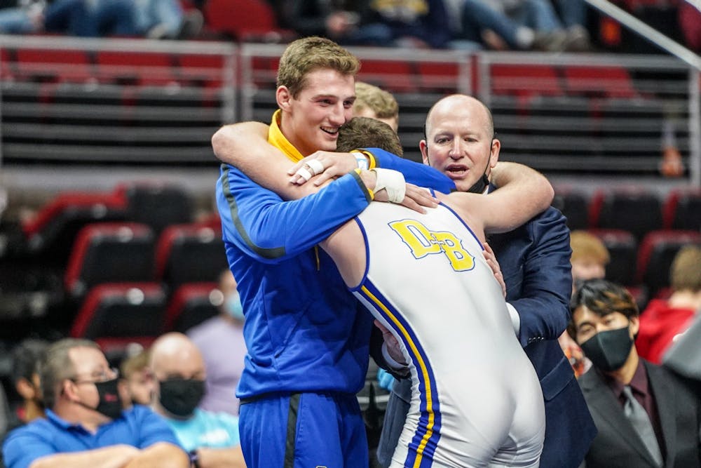 Carson Tenold (white) hugs his twin brother Cade (blue) after Carson won the 182-pound 1A state title. Photo courtesy of Cam Kramer. 