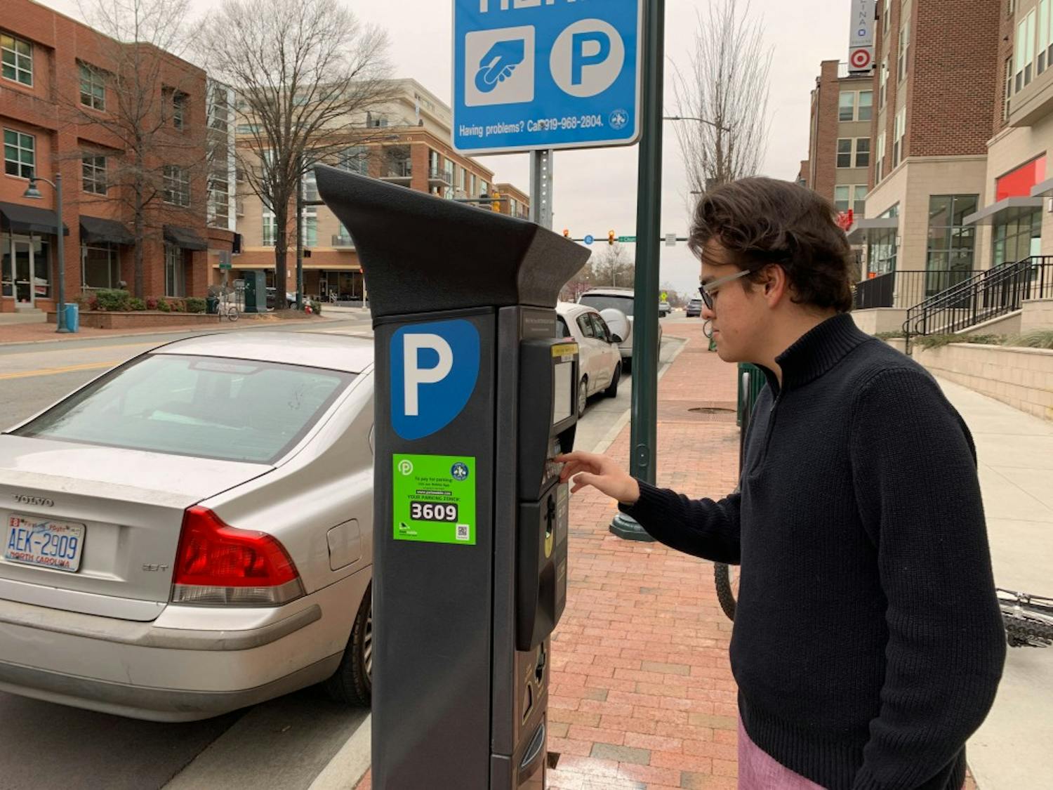 Community member Stefan Hartelt interacts with the parking meter outside of Target on Franklin Street.