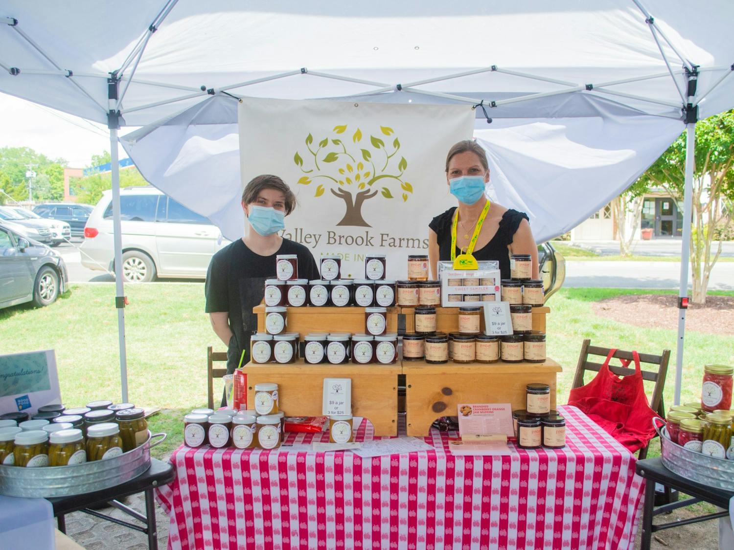 Andrea Davis, owner of Valley Brook Farms, stands with co-worker Matthew Pittman behind their booth at the Carrboro Farmers Market on Wednesday June 9, 2021. Valley Brook Farms is a local farm that makes a variety of jams, jellies, and pickled goods.