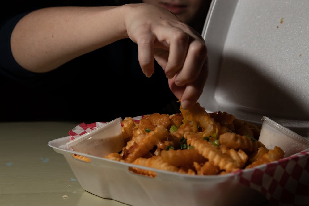 DTH Photo Illustration. An individual enjoys a takeout order of fries.