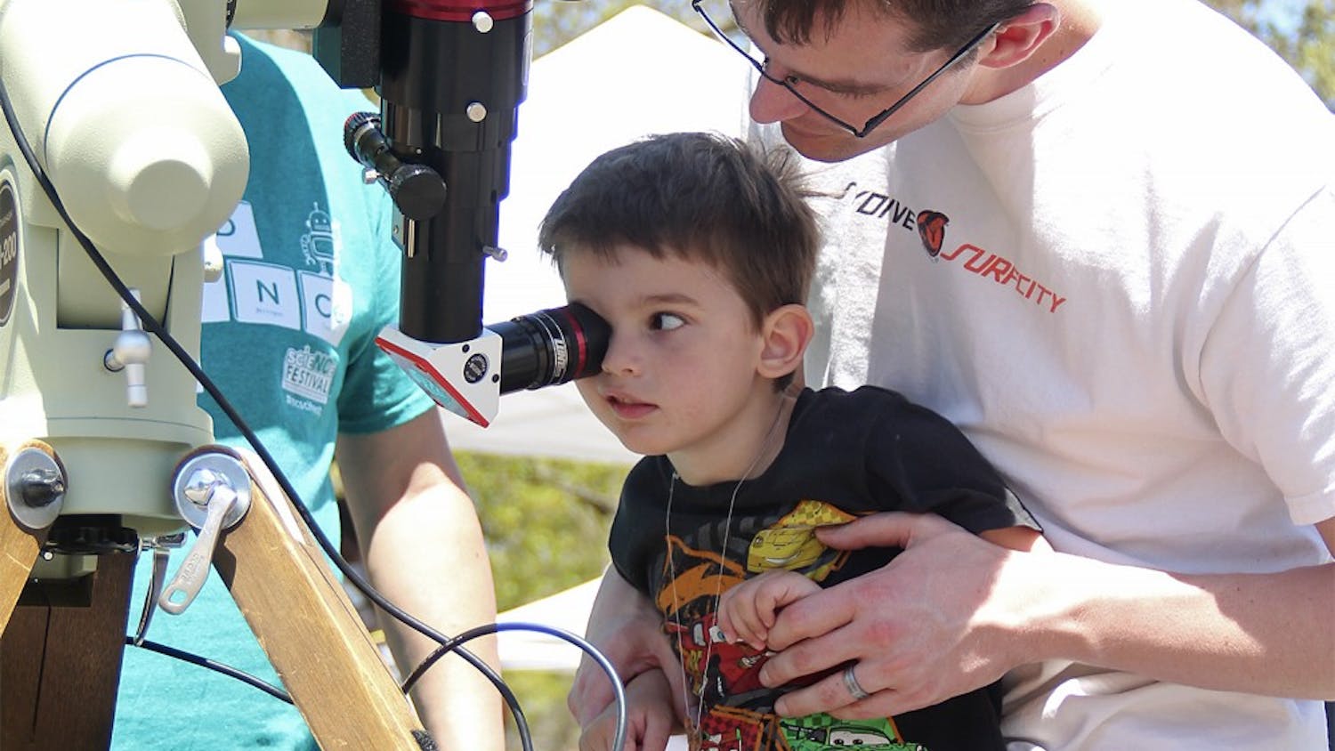Max Brueseke looks through a telescope with the help of his father at the NC Science Expo on Saturday. 