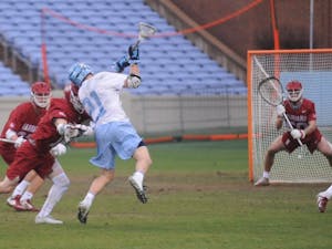 Midfielder Justin Anderson (21) shoots during the game against Harvard in Kenan Stadium on Saturday, Feb. 16, 2019. UNC won 16-11. 