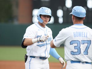 UNC freshman infielder Danny Serretti (1) and assistant coach Jason Howell fist bump after a hit by Serretti during a home game at Boshamer Stadium against Appalachian State on Tuesday, March 22, 2022.