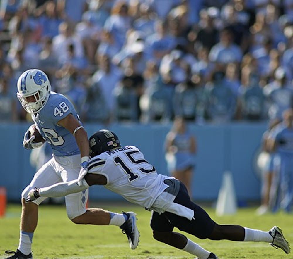<p>UNC wide receiver Thomas Jackson (48) sheds a tackle attempt by Pittsburgh defensive back Reggie Mitchell (15) as he runs upfield.</p>