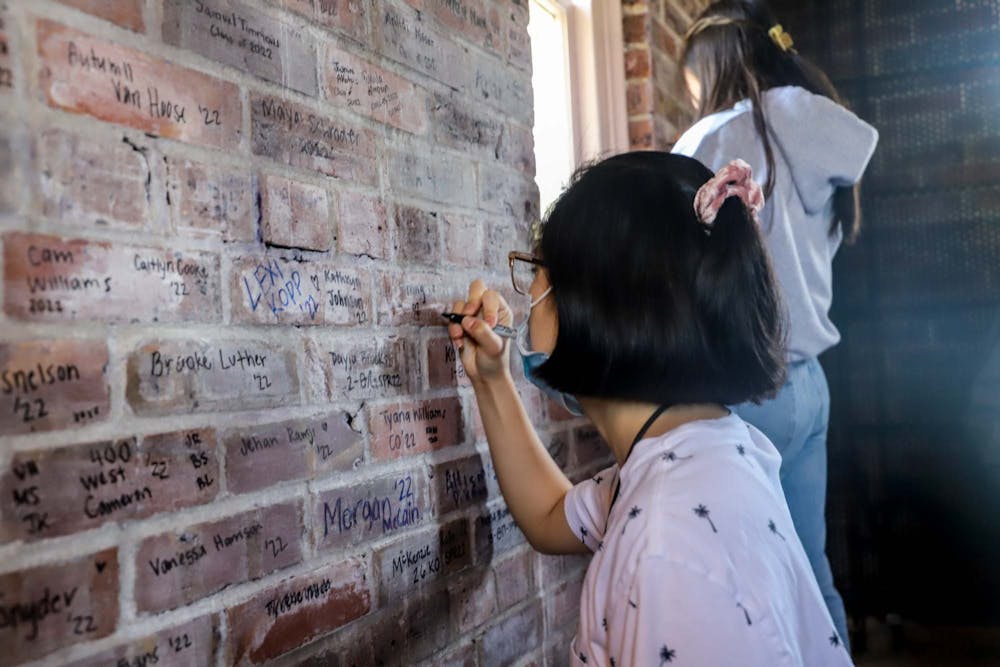 <p>Senior human development and family studies major Trang Le signs her name at the top of the Morehead-Patterson Bell Tower on Wednesday, April 20, 2022.</p>