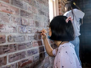 Senior human development and family studies major Trang Le signs her name at the top of the Morehead-Patterson Bell Tower on Wednesday, April 20, 2022.