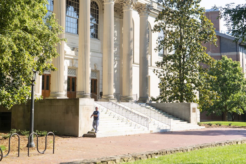 <p>A summer facilities worker walks to the edge of Wilson Library while wearing a mask as a precautionary measure against COVID-19 on Sunday, June 7, 2020.</p>