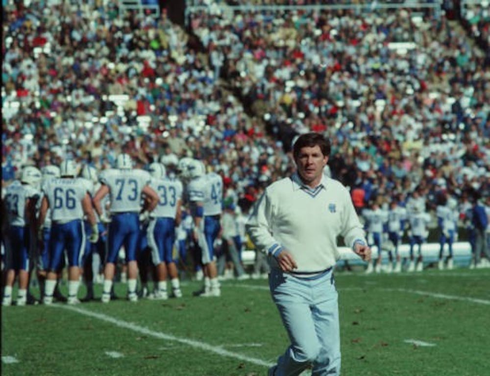 UNC Head Coach Mack Brown runs on the field during a game versus Duke in Kenan Memorial Stadium on Nov. 11, 1989. In the Hugh Morton Photographs and Films #P0081, copyright 1989, 1989, North Carolina Collection, University of North Carolina at Chapel Hill Library.