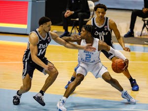 Duke senior guard Jordan Goldwire (14) and sophomore forward Wendell Moore Jr. (0) defend UNC freshman guard Caleb Love (2) in the Dean Dome on March 6, 2021. The Tar Heels beat the Blue Devils 91-73.