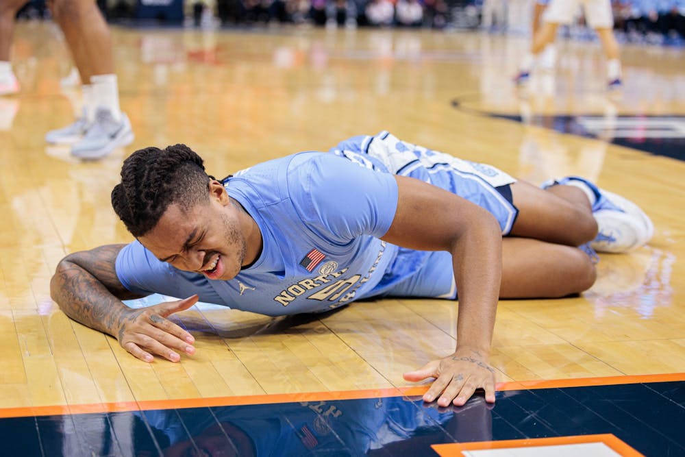 <p>UNC senior Armando Bacot (5) goes down following an injury in the first half during a game against UVA at John Paul Jones Arena in Charlottesville, VA on January 10, 2023. UNC lost 65-58. Photo courtesy of Ryan Hunt.</p>