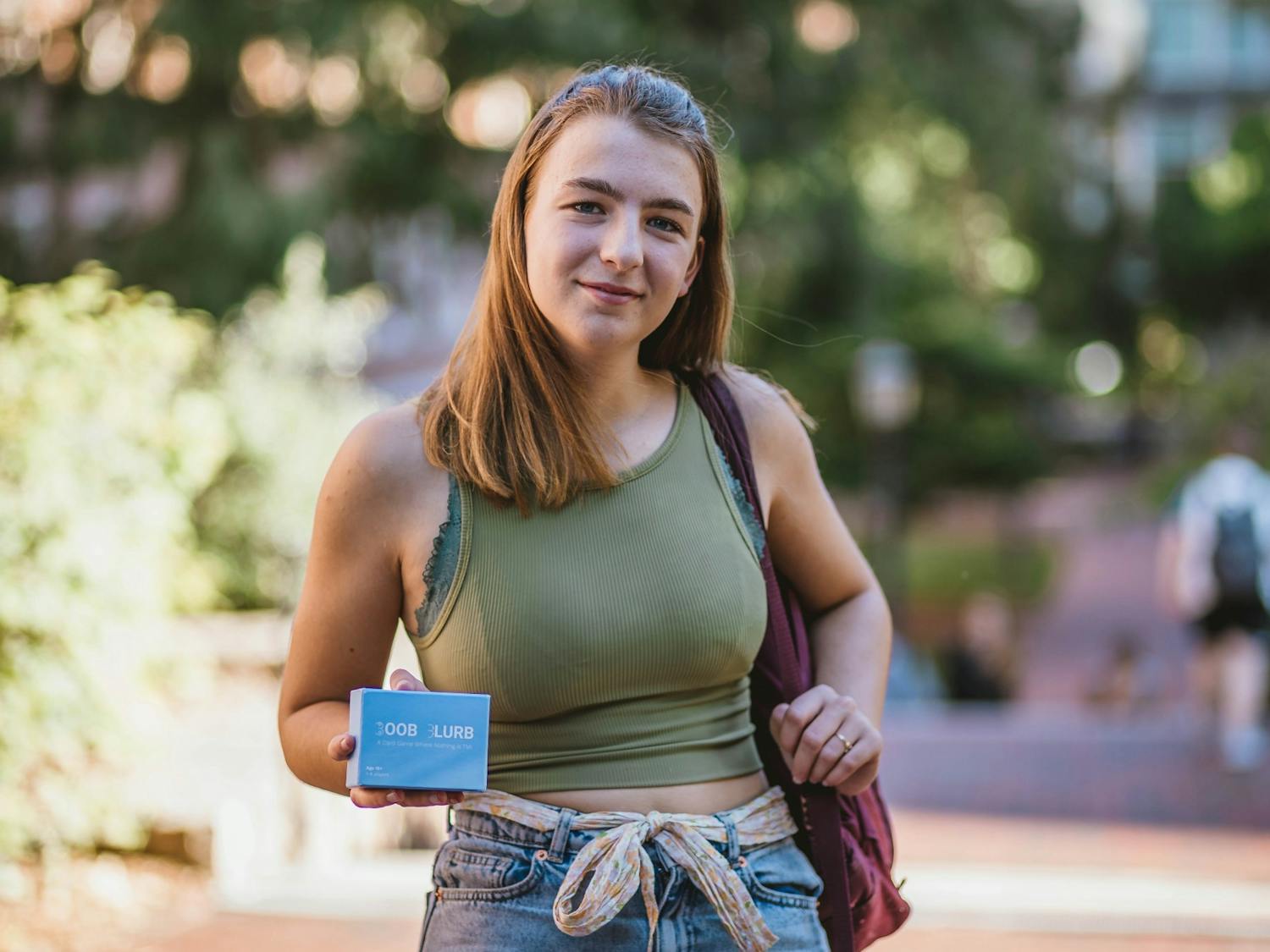 With a backpack and a water bottle, sophomore Izzy Grandic walked around campus for over thirteen straight hours  to raise awareness about inaccessible healthcare. She poses with her card game, Boob Blurb, on Wednesday, Sept. 21, 2022.