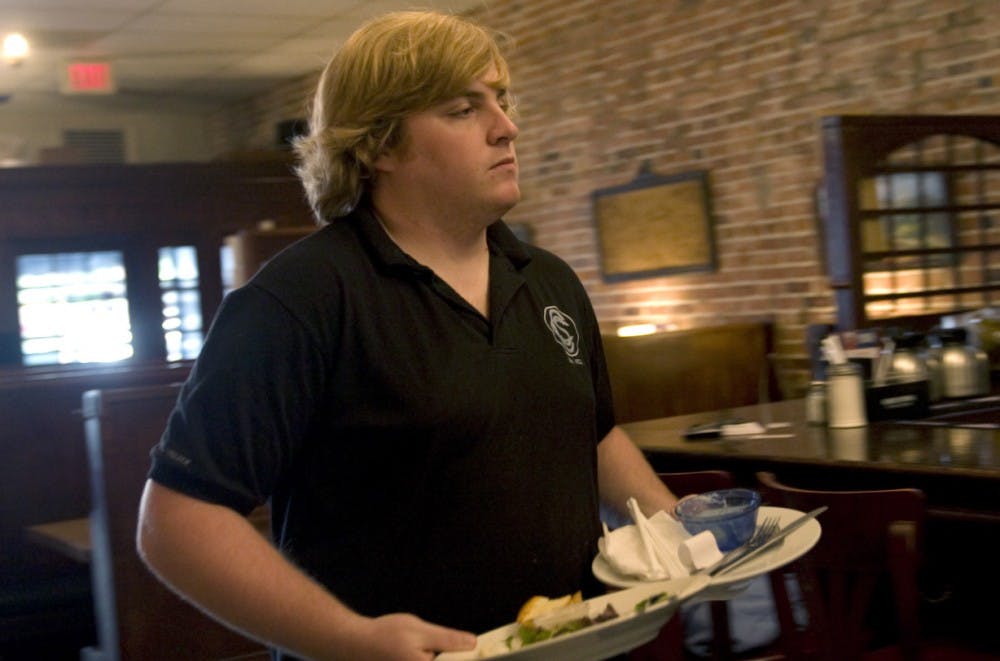 Waiter Will Phelan, 23, clears a table at Carolina Coffee Shop on Tuesday. Phelan, of Hillsborough, has worked at Carolina Coffee Shop for two years. Carolina Coffee Shop joined 103 restaurants for RSVVP, which raised funds for the Inter-Faith Council for Social Service.