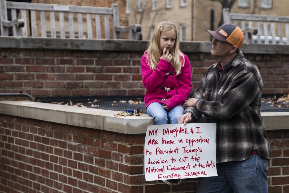 James Strong and his daughter, Avery, protest President Trump’s decision cut tuning to the National Endowment of the Arts in January.