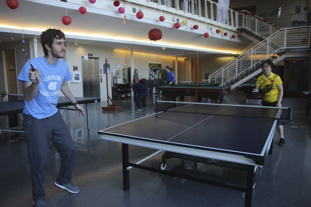 UNC sophomore and club table tennis member Abraham Post serves the ball to his opponent Wei Qu, a member of the senior citizen team. 