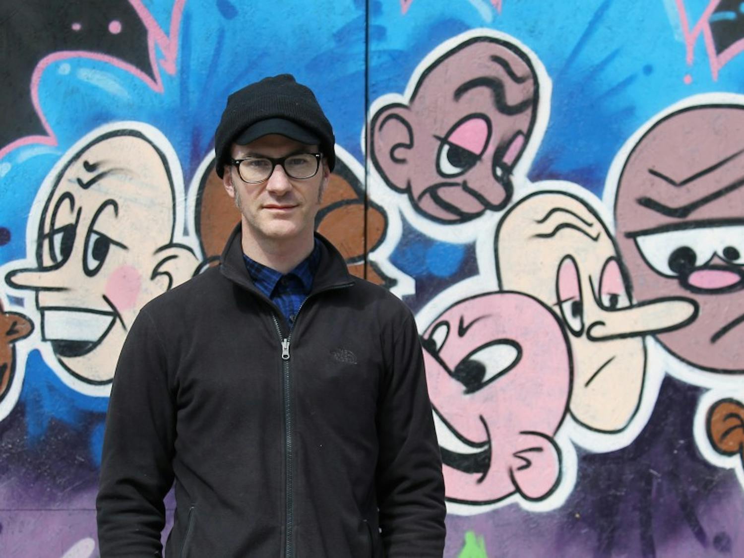 Local artist Casey Robertson poses by his graffiti at the Waffle House on Franklin Street. 