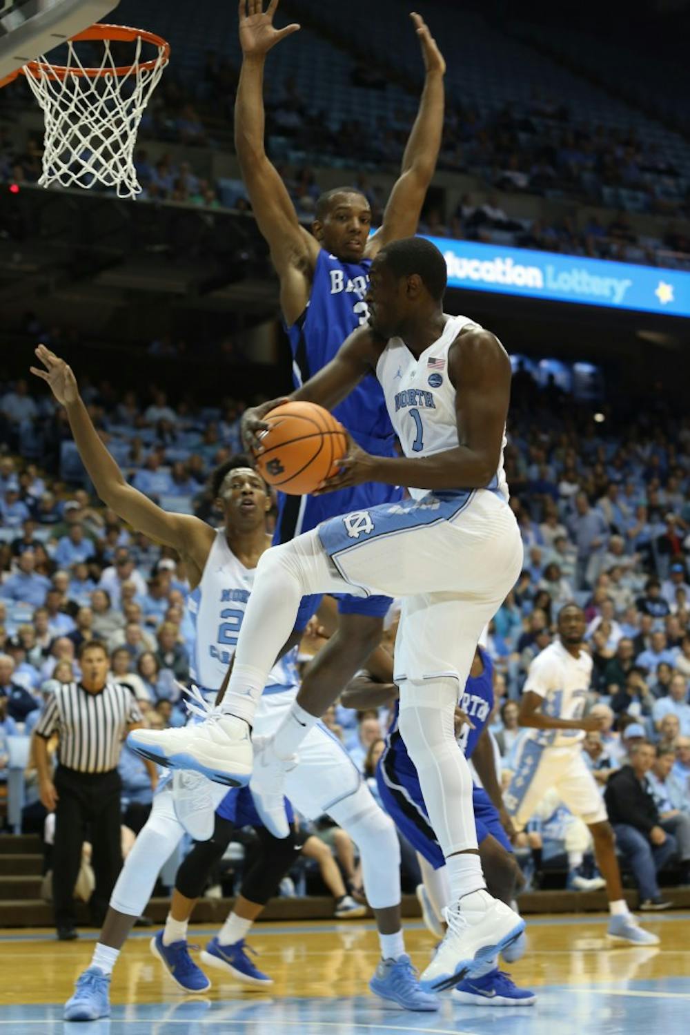 <p>Forward Theo Pinson (1) drops off a pass for forward Sterling Manley (21) against Barton College on Friday night in the Smith Center.&nbsp;</p>
