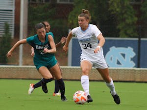First-year defender Tessa Dellarose (34) looks for an open pass as she dribbles down the field. UNC won 2-0 against UNCW at home on Sunday, Aug. 21, 2022.