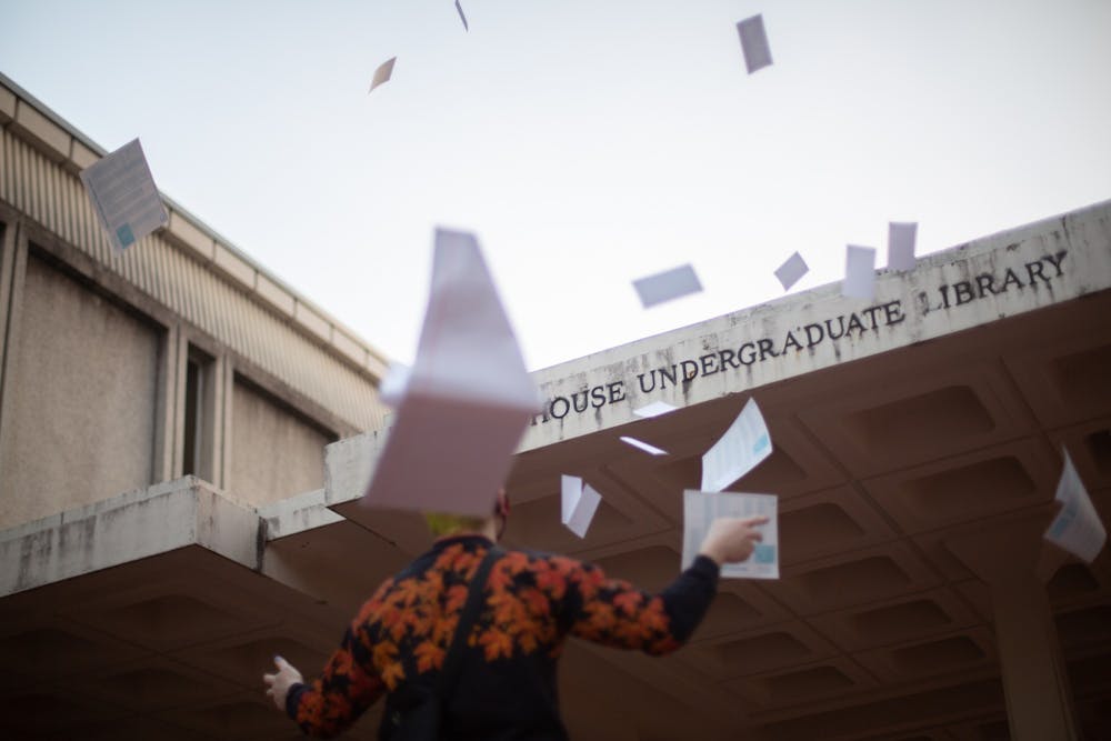 DTH Photo Illustration. A student throws test materials in the air. UNC, along with other universities, waived their SAT requirement for admissions, providing relief to many applicants. 