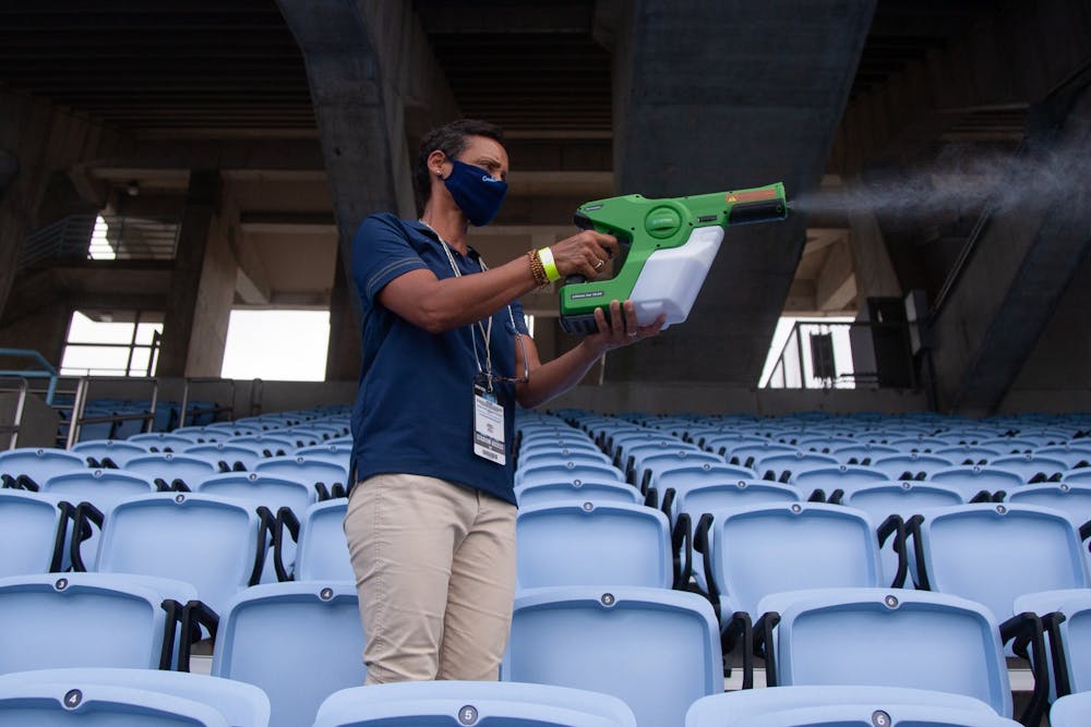 <p>UNC athletic facilities worker Jaci Field disinfects the seats in Kenan Memorial Stadium after a football game against Syracuse on Saturday, Sept. 12, 2020.&nbsp;</p>