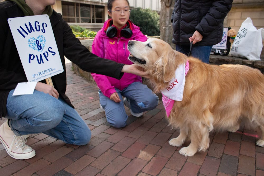<p>UNC first-years AJ Kinrade and Tianyun Zhao play with Roxy the Golden Retriever in Chapel Hill, N.C. on Monday, Jan. 16, 2023. Roxy visits campus with HAPPEE, an organization created to improve college students’ mental health by providing emotional support and outreach.</p>