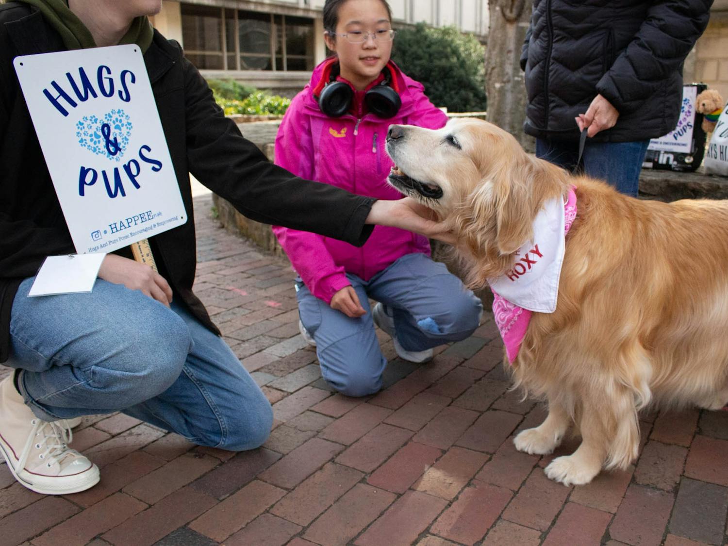 UNC first-years AJ Kinrade and Tianyun Zhao play with Roxy the Golden Retriever in Chapel Hill, N.C. on Monday, Jan. 16, 2023. Roxy visits campus with HAPPEE, an organization created to improve college students’ mental health by providing emotional support and outreach.