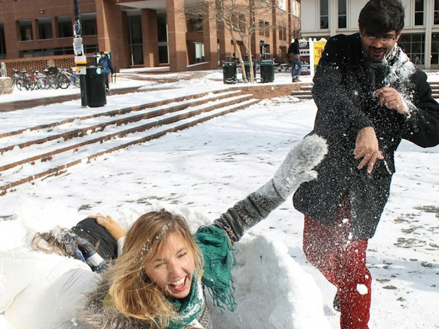 Grad student, Asadullah Naweed throws snowballs at sophomores Cyara De Lannoy and Cassy Karlsson. "You can't hit us, we have a fort for protection!" Karlsson said.  The girls had been taking shifts guarding their fort all day, because people had been trying to take it.