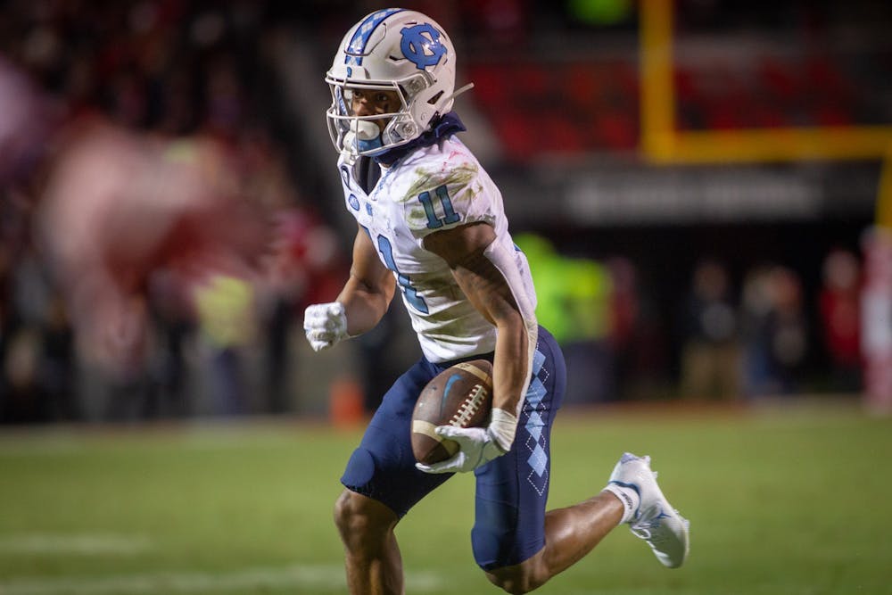 UNC sophomore wide receiver Josh Downs (11) makes progress down the field during the Tar Heels' football game against the N.C. State Wolfpack at Carter Finley Stadium in Raleigh, NC, on Friday, Nov. 26, 2021. UNC lost 34-30.