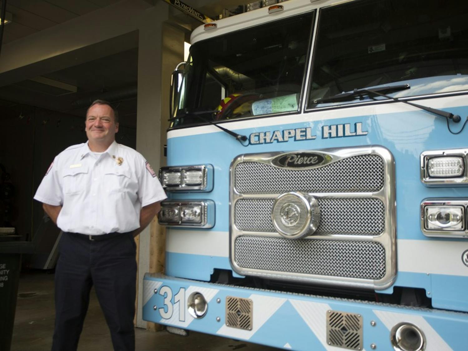 Chief Sullivan poses next to one of the well-known blue fire trucks at the Chapel Hill Fire Department on Friday, Oct. 4, 2019. 