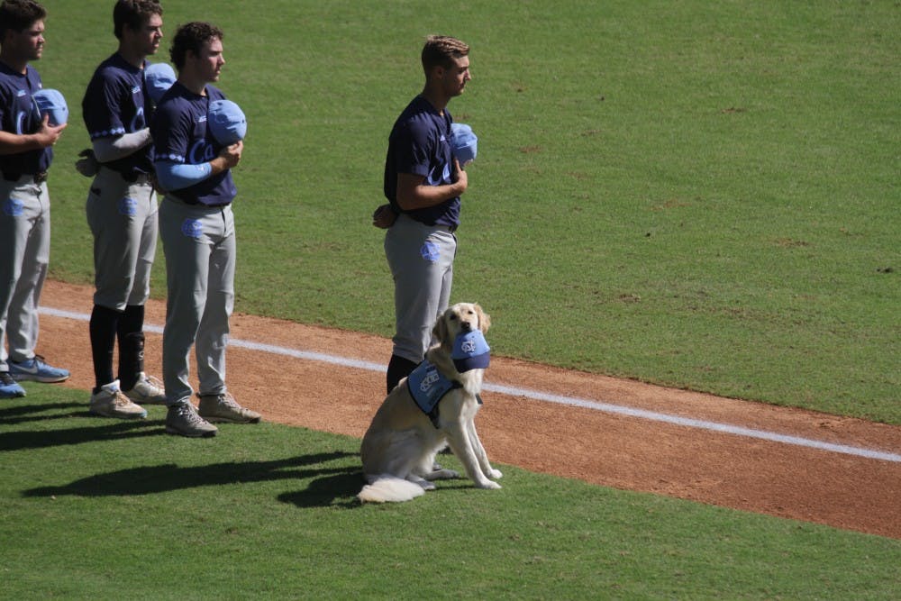 Remington joins the North Carolina baseball team on the field for the national anthem before Sunday's Fall World Series intrasquad scrimmage.&nbsp;