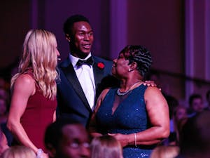 Emcees Marika Akkerman (women's tennis) and Kenny Selmon (track and field) present Gwen Warren with the Unsung Hero Award at the Rammys on April 23 in Memorial Hall.
