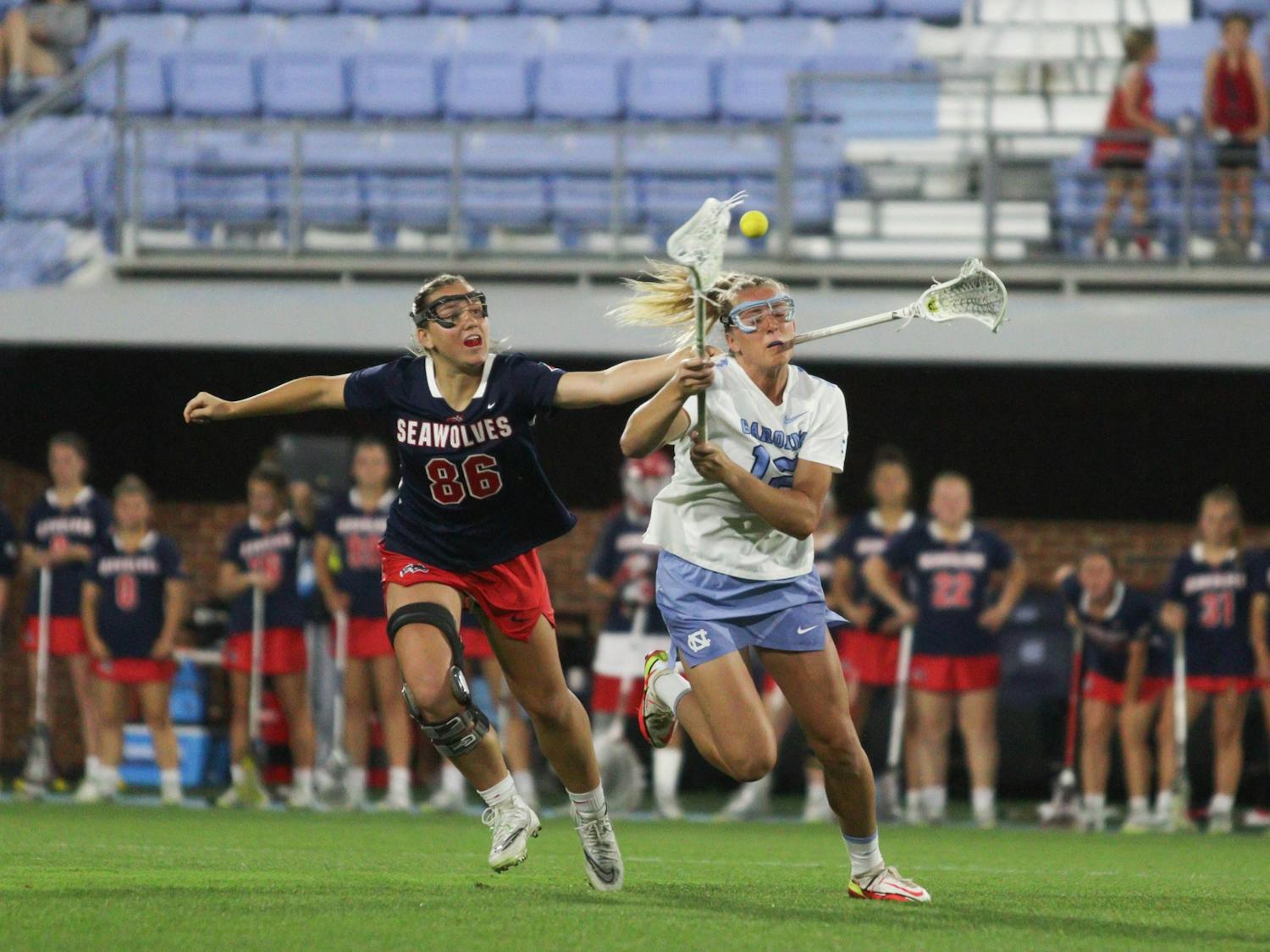 Graduate midfielder Ally Mastroianni (12) flings the ball with Stony Brook defense right behind her. UNC won 8-5 against Stony Brook in the NCAA Quarterfinals at home on Thursday, May 19, 2022.