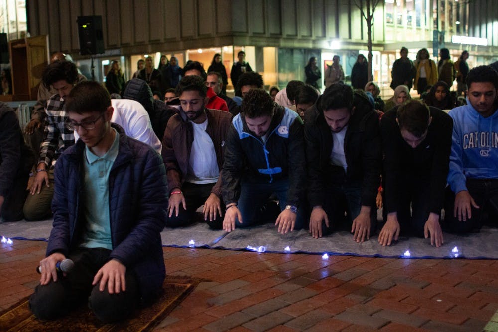 Students and community members join each other in a prayer led by sophomore computer science major and mathematics minor Omar Shaban (left) following a vigil hosted by the Muslim Student Association outside of the Student Union on Thursday, March 21, 2019. The event honored the victims of the Christchurch shooting in New Zealand, during which a shooter claimed the lives of 51 people during Friday Prayer. 