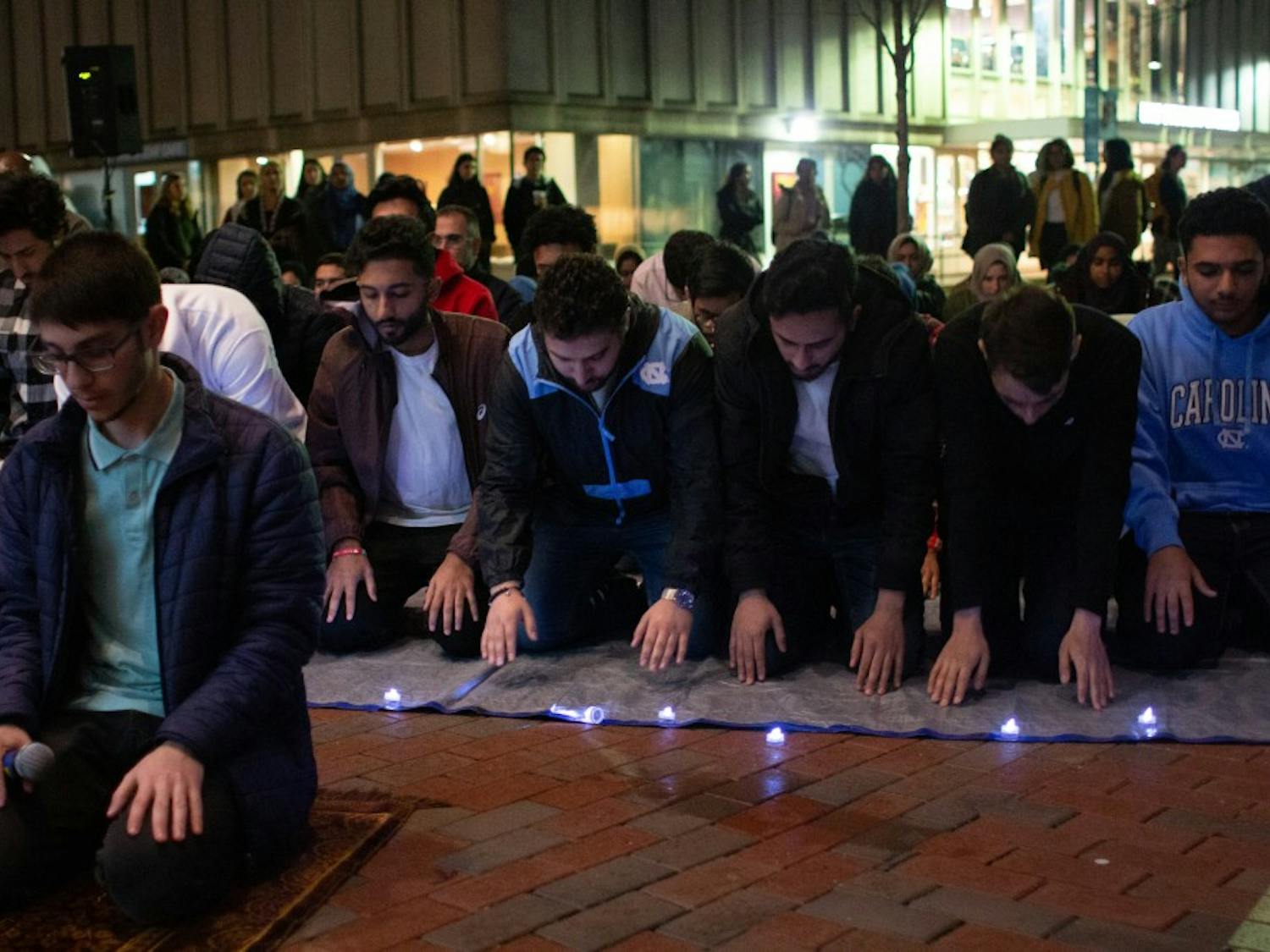 Students and community members join each other in a prayer led by sophomore computer science major and mathematics minor Omar Shaban (left) following a vigil hosted by the Muslim Student Association outside of the Student Union on Thursday, March 21, 2019. The event honored the victims of the Christchurch shooting in New Zealand, during which a shooter claimed the lives of 51 people during Friday Prayer. 