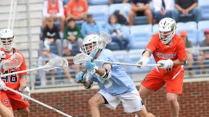 Senior midfielder Harrison Schertzinger (5) gets blocked by Syracuse defense while having the ball. UNC beat Syracuse 14-13 at home on Saturday, April 16, 2022.