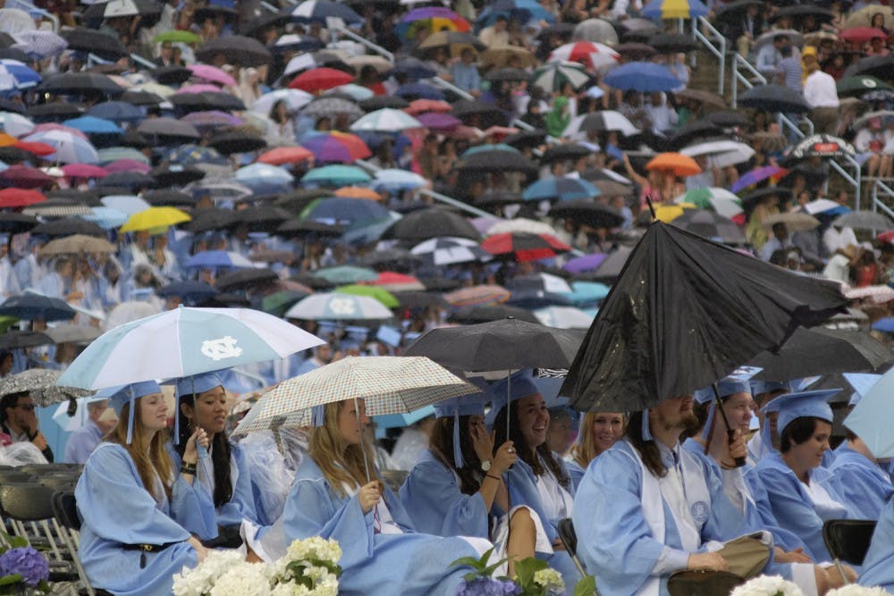 Students try to stay dry at the class of 2015's graduation ceremony Sunday morning.