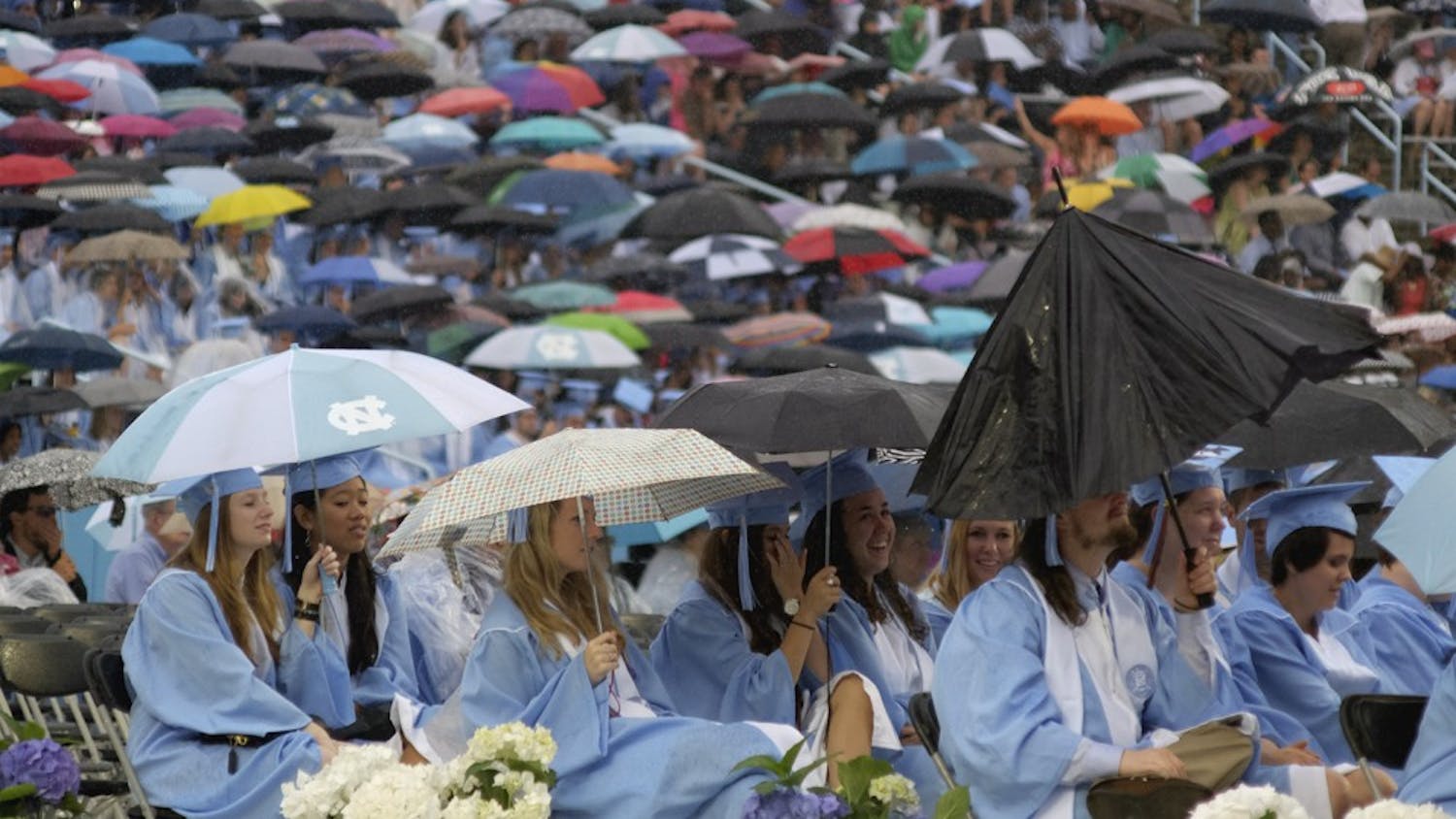 Students try to stay dry at the class of 2015's graduation ceremony Sunday morning.