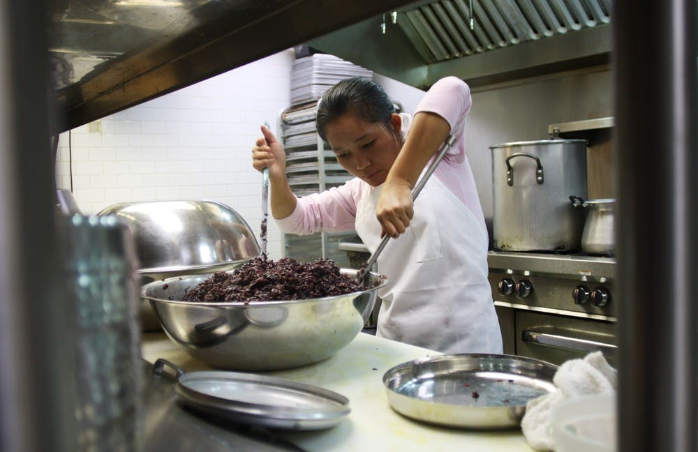 	Khai Tow cooks black rice for dinner at the Transplanting Traditions Community Farm Autumn Fundraiser at Vimala’s Curryblossom Cafe.