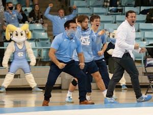 Head coach Coleman Scott celebrates along with Associate Head Coach Tony Ramos and other wrestlers at the wrestling match against Duke University on Friday, Jan. 21, 2022. UNC won 29-6.