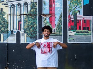 Eliam Mussie, the co-president of the Black Entrepreneur Initiative, pictured in front of the "Greetings from Chapel Hill" mural on Rosemary Street in Chapel Hill, N.C. on Tuesday, Sept. 6, 2022. Mussie is wearing a shirt from his clothing brand, Franklin Street Market, which will be represented at the pop-up this coming Saturday, Sept. 10, 2022.